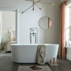 Modern bathroom with freestanding bathtub, round mirror, and pink curtains.
