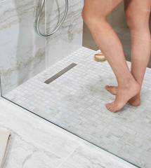 wetroom with white/grey mosaic tiles short linear drain and ladies legs
